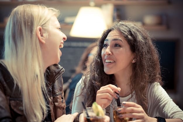 A close-up shot of two friends sitting at a cafe, one looking concerned while the other speaks animatedly, showing a moment of tense conversation.