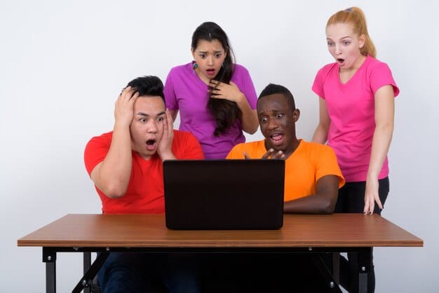 Two employees looking confused while reading a group chat message on their laptops, with question marks floating above their heads.
