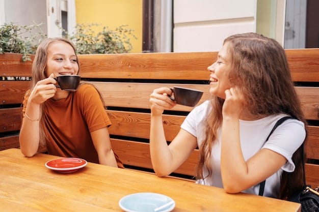 Two friends talking face-to-face in a coffee shop, one is showing the other something on their phone. The atmosphere is friendly but slightly serious, suggesting a conversation about online boundaries.