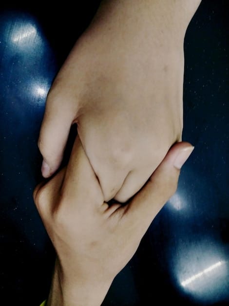 A close-up shot of two people's hands intertwined, symbolizing trust and emotional support in a relationship.