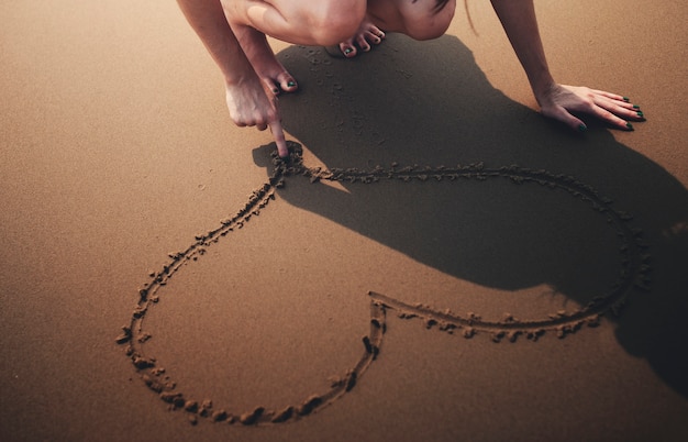 A person drawing a line in the sand, symbolizing the act of setting boundaries in a relationship and protecting personal space from disrespect.