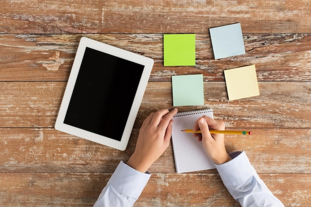 A person meticulously planning an online event on a tablet, surrounded by sticky notes with ideas, illustrating the detailed preparation involved.